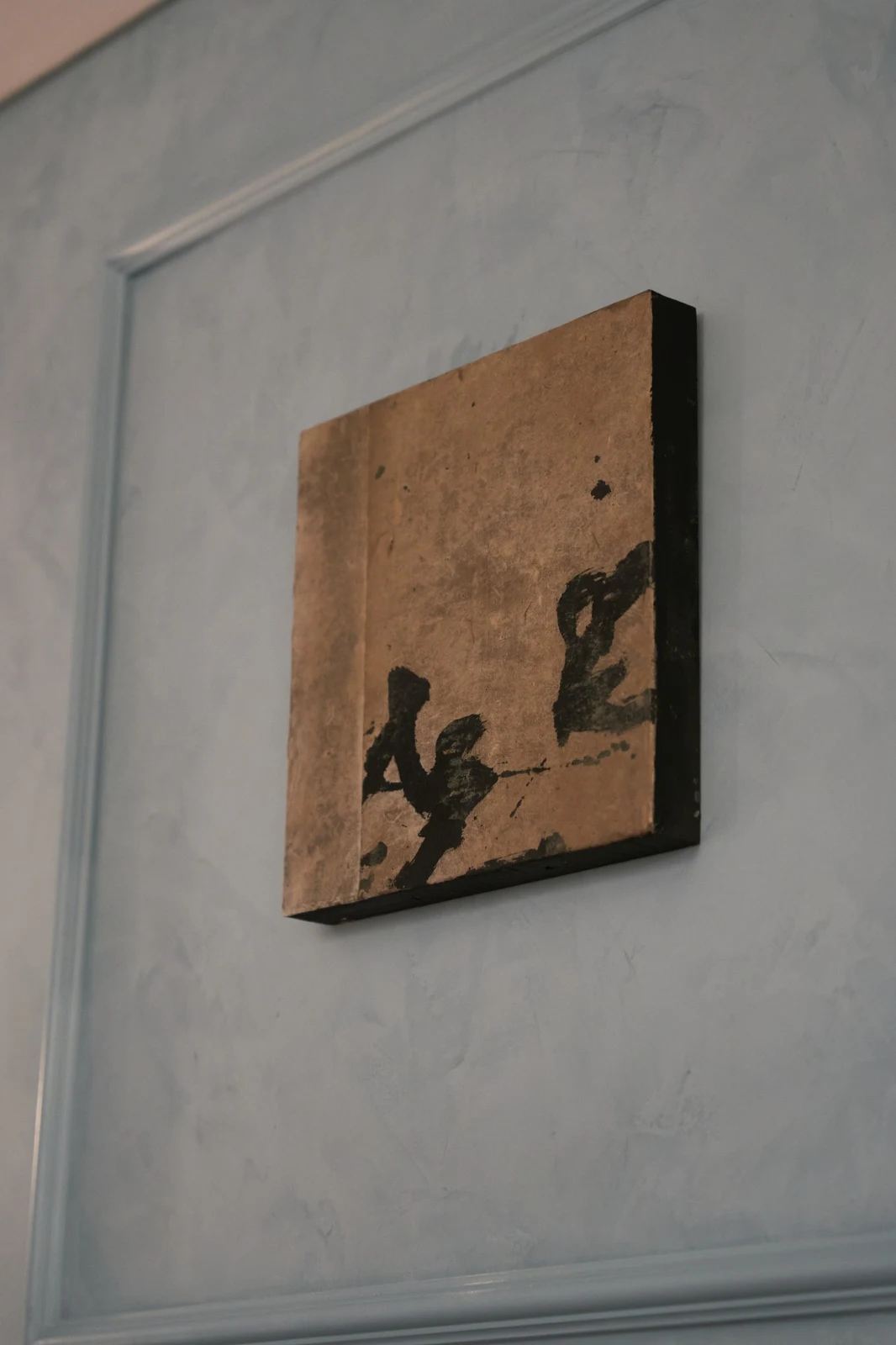 Untitled (GES#3) by Alexandra Yan Wong, seen at an angle on a blue plaster wall, showing the canvas edge