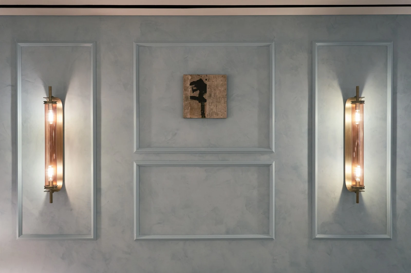 Untitled (GES#4) by Alexandra Yan Wong, hung between two brass wall lights on a pale plaster wall