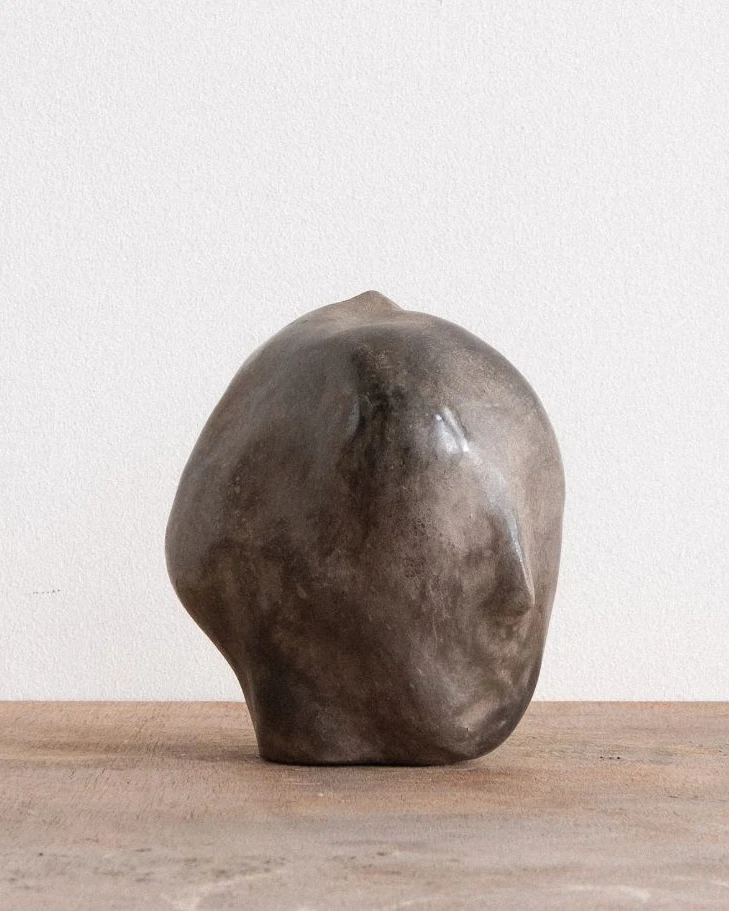 All Our Gods Are Dancing Gods by Arran Gregory, a smooth grey burnished clay head with a pointed crown, its face turned to the right