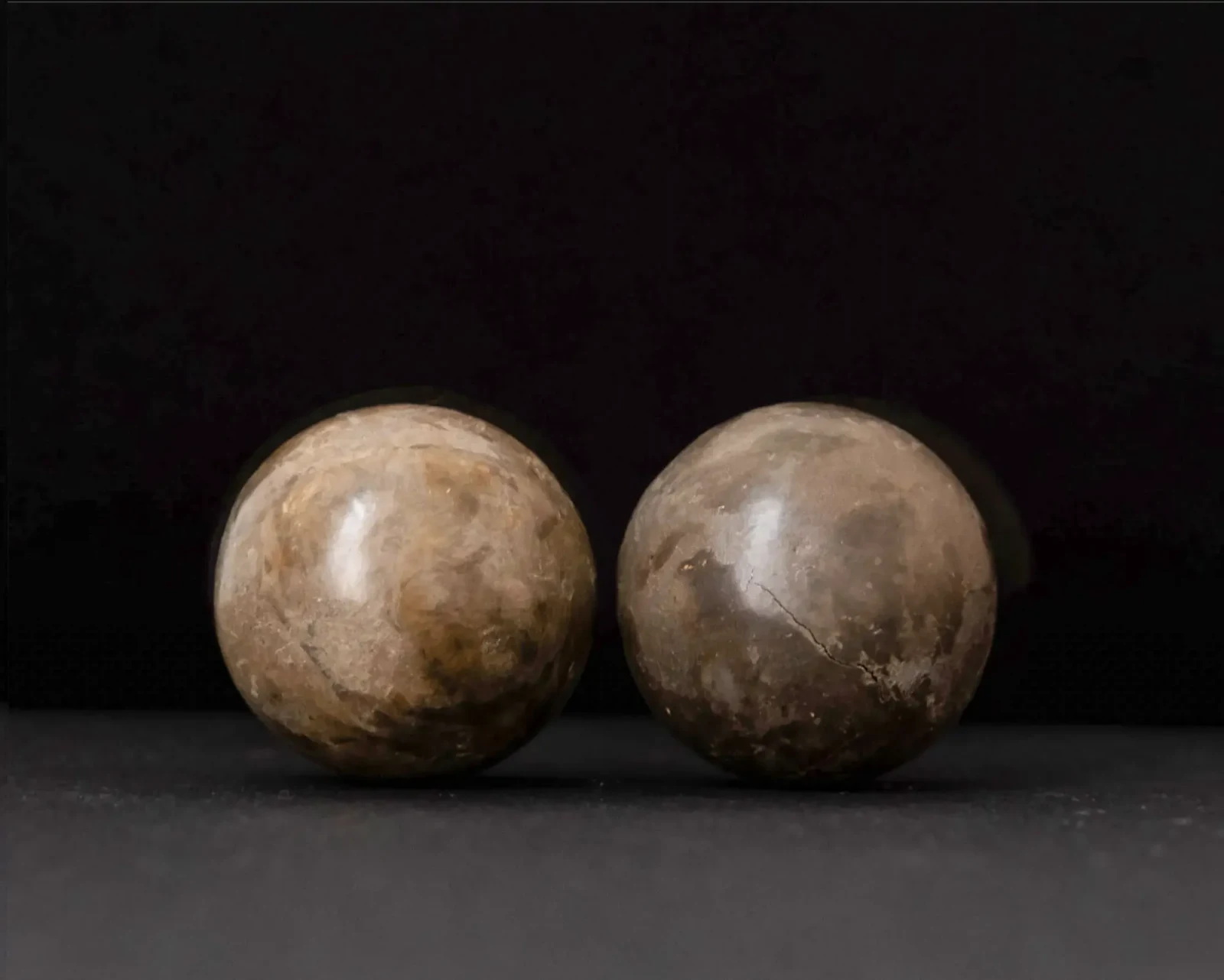 Meditation Balls by Arran Gregory, two marbled burnished clay spheres side by side against a black background