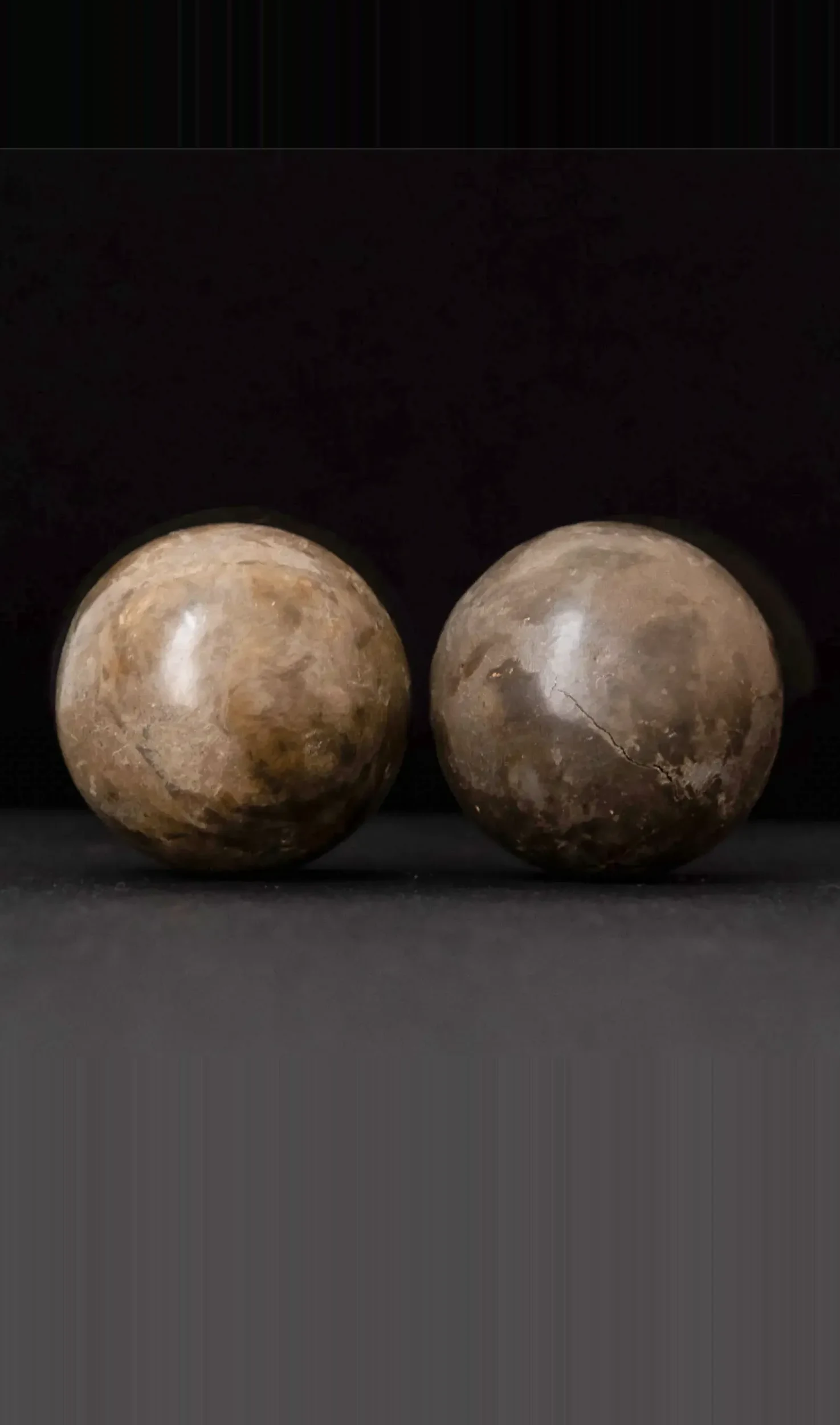 Meditation Balls by Arran Gregory, two marbled burnished clay spheres side by side against a black background