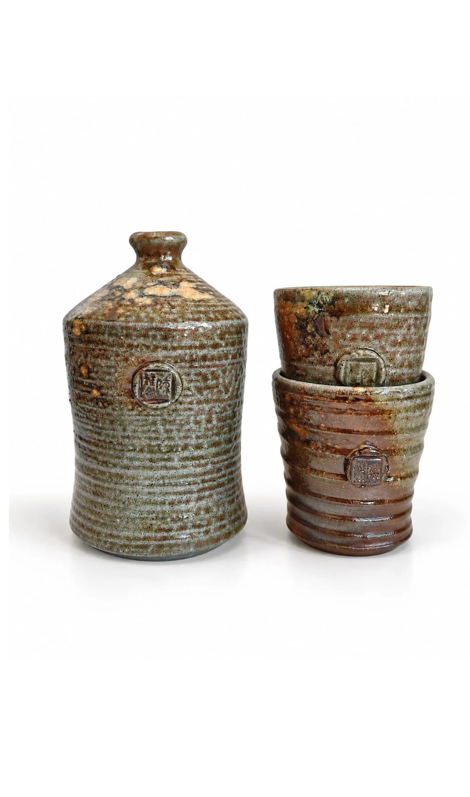 Sake Set #1 by Jacob Chan, a waisted green and rust soda-fired bottle beside two stacked ribbed cups