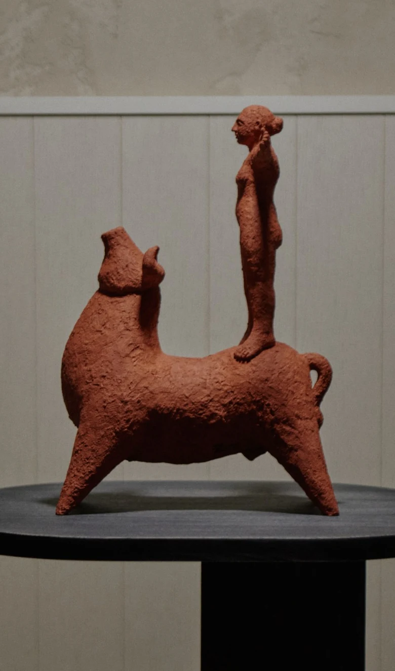 Beauty and the Beast by Zahed Tajeddin, a terracotta bull with a standing figure on its back, on a black wooden plinth