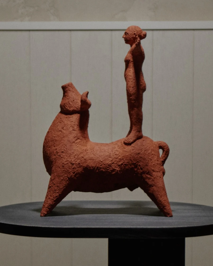 Beauty and the Beast by Zahed Tajeddin, a terracotta bull with a standing figure on its back, on a black wooden plinth